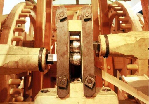 Close-up of a wooden roller-press mechanism with geared cylinders, photographed at the Hall mint