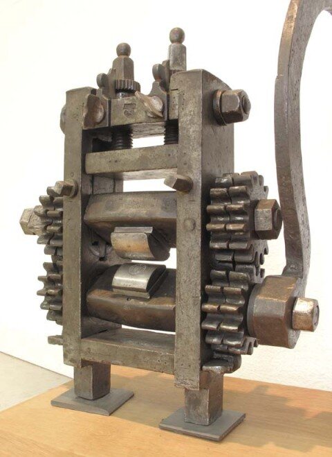A geared rocker-die mechanism for coin striking